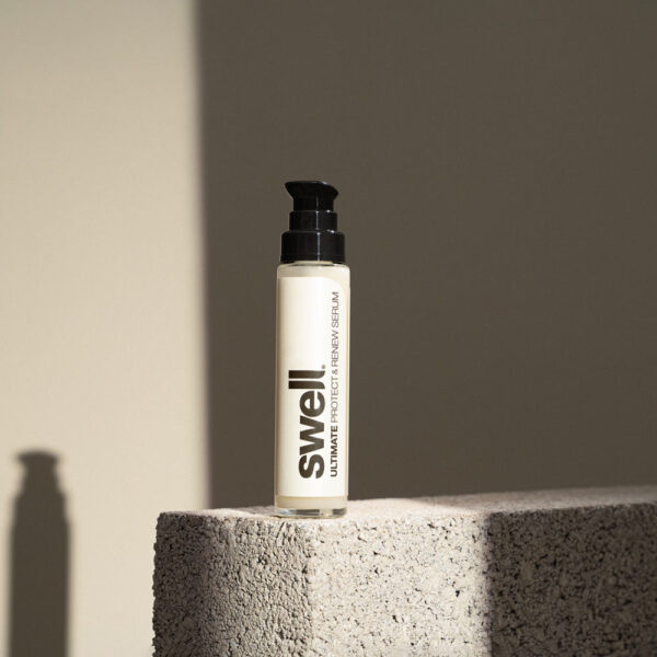 A bottle of Swell hair serum on a stone background